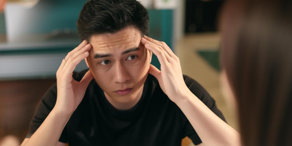 Realistic photo of a man in Singapore looking frustrated or experiencing a headache after a romantic moment, soft lighting